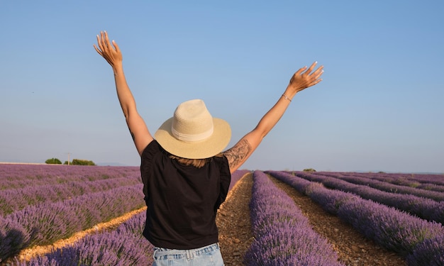 Young woman with outstretched arms enjoying freedom and life in front of lavender fields traveler