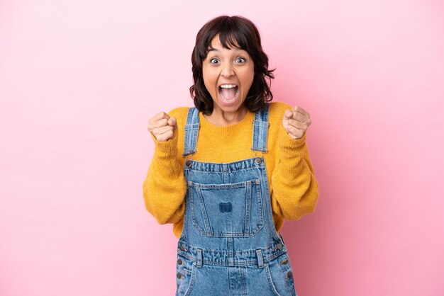 Young woman with overalls isolated background celebrating a victory in winner position