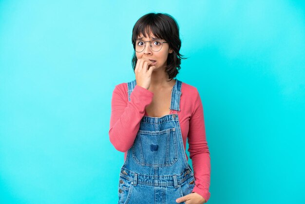 Young woman with overalls isolated background nervous and scared