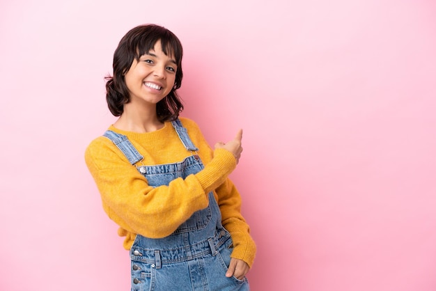 Young woman with overalls isolated background pointing back