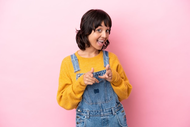 Young woman with overalls isolated background pointing to the front and smiling
