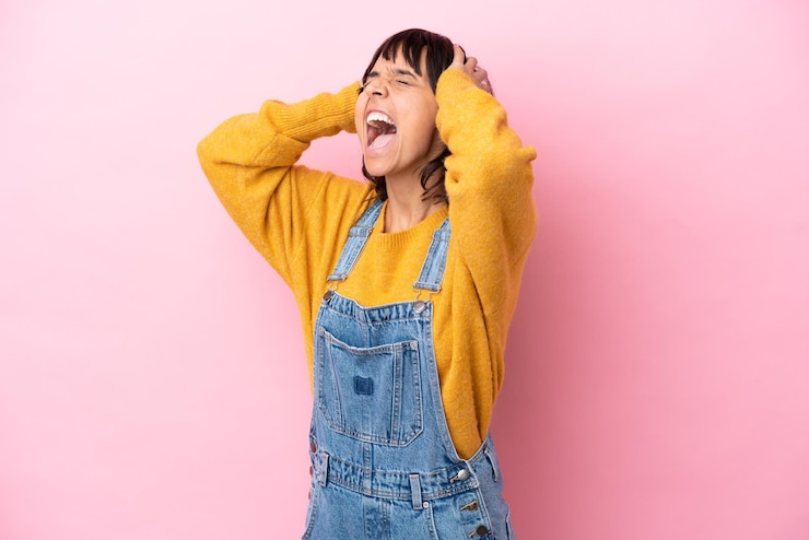 Photo オーバーオールの孤立した背景を持つ若い女性は圧倒されます