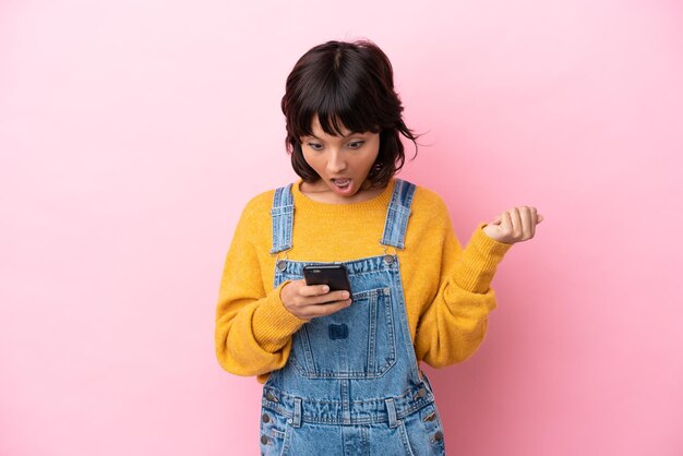 Young woman with overalls isolated background surprised and sending a message