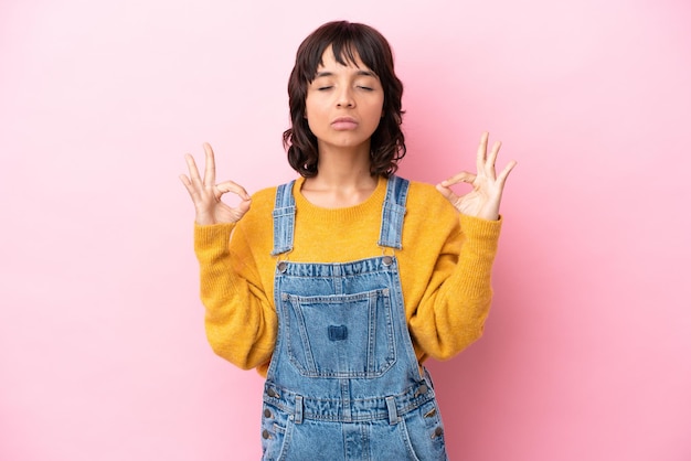 Young woman with overalls isolated background in zen pose