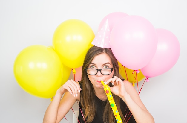 Young woman with party hat with noisemaker on a white background.