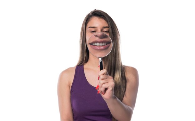 young woman with perfect smile and healthy teeth behind magnifying glass