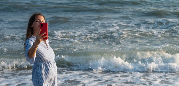 海沿いの電話を持つ若い女性。