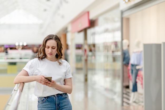 Selfieを作る彼女の手に携帯電話を持つ若い女。