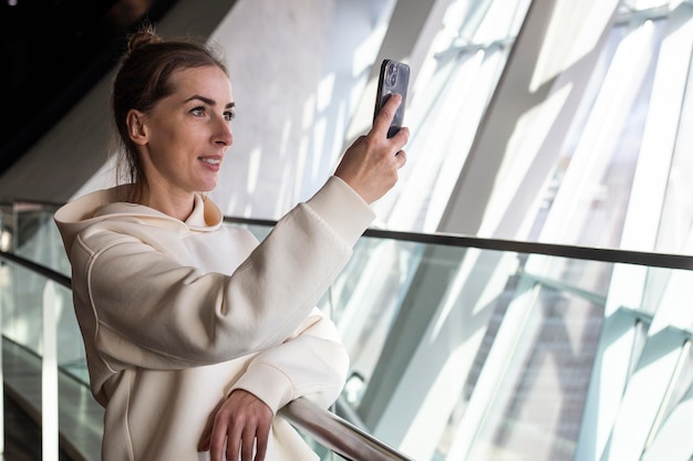 Young woman with a phone takes a photo from the window on a panoramic view