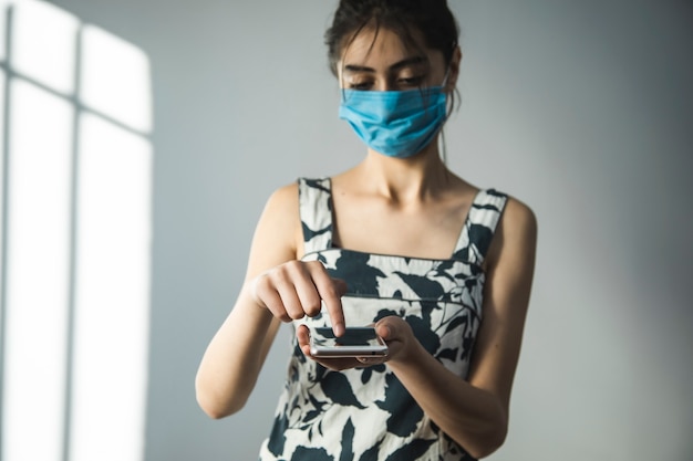 A young woman with a phone and wear a mask