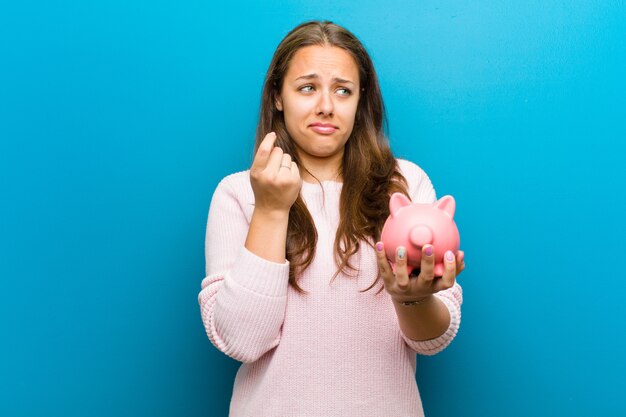 Young woman with a piggy bank on blue