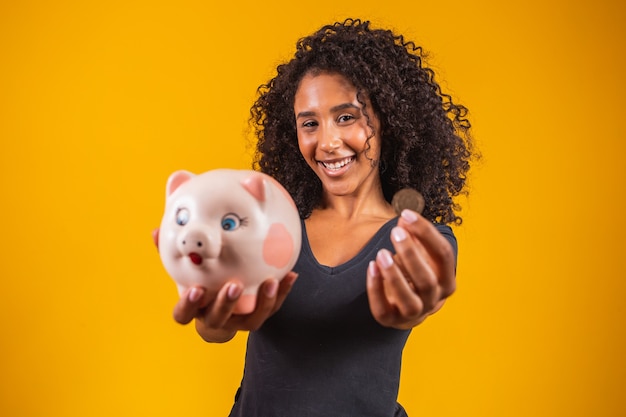 Young woman with a piggy bank on a solid background