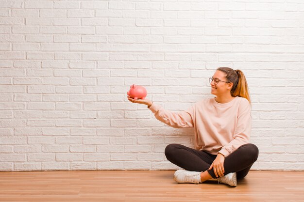 貯金箱を持つ若い女性