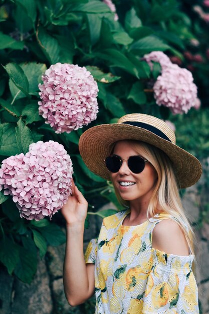 Young woman with pink flower on plant