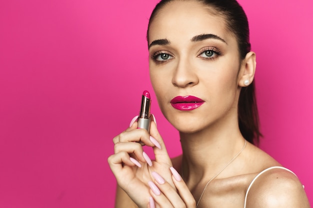 Foto giovane donna con le labbra rosa guardando il rossetto