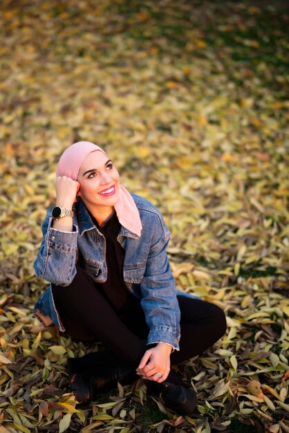 Молодая женщина с розовым шарфом на голове в парке