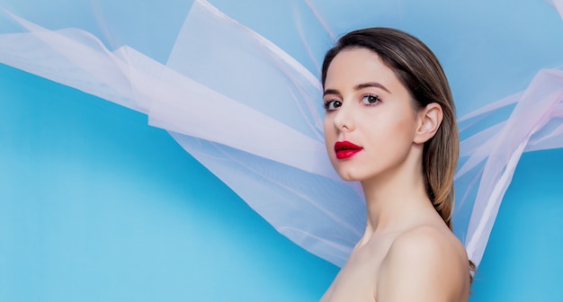 Young woman with pink tulle on blue background