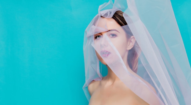 Young woman with pink tulle on blue background