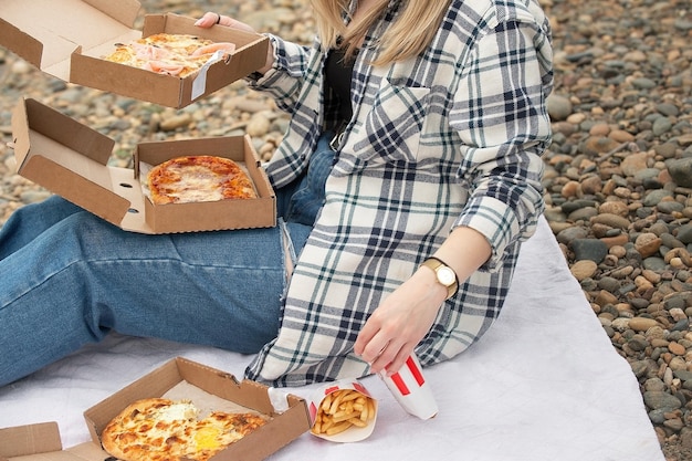 Young woman with pizza boxes at a picnic in nature