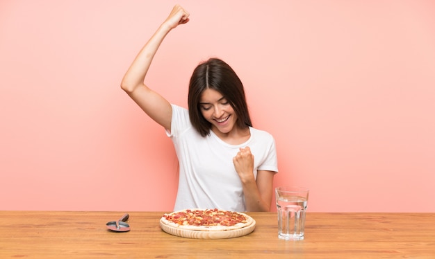 Giovane donna con una pizza che celebra una vittoria