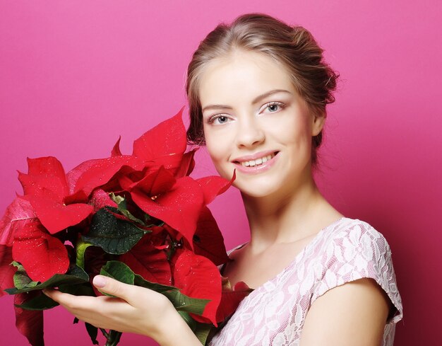 Young woman with poinsettia over pink 