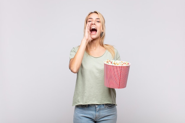 Young woman with a pop corns bucket feeling happy, excited and positive