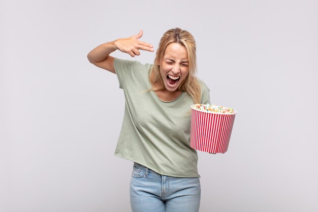 Young woman with a popcorn bucket looking unhappy and stressed