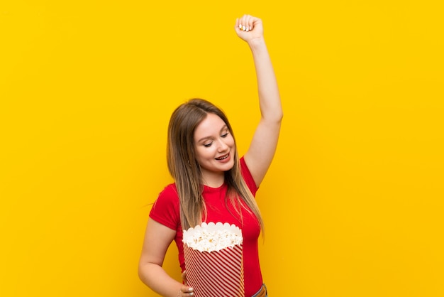 Giovane donna con popcorn sul muro rosa per celebrare una vittoria