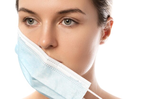 Photo young woman with prevention mask and skin irritation on white background. maskne - acne breakouts from wearing a face mask.