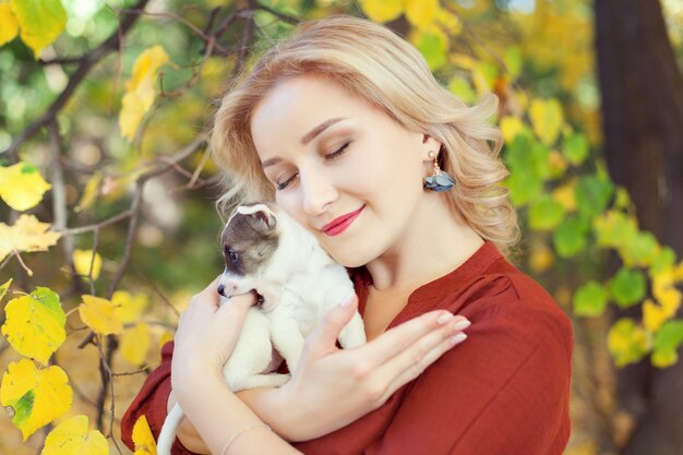 Young woman with a puppy in autumn park