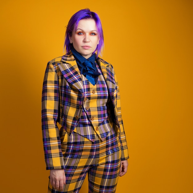 Young woman with purple hair in a stylish bright plaid suit