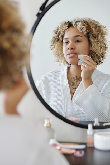 Young woman with quartz scraper massaging her face