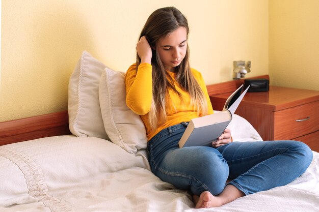 Young woman with reading sitting on bed