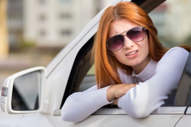 Young woman with red hair driving a car.