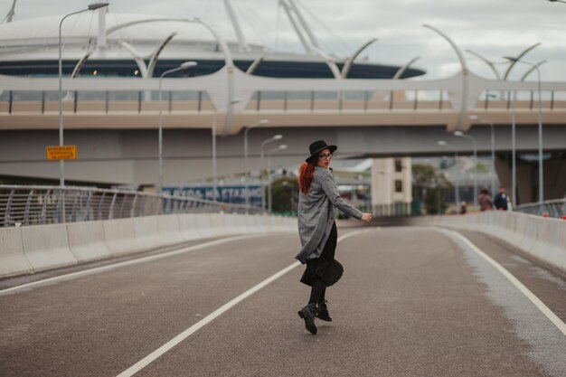 Young woman with red hair jumping and running on the road