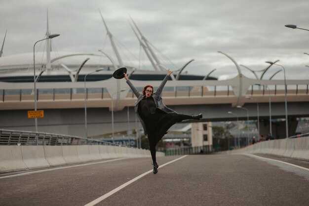 Young woman with red hair jumping and running on the road