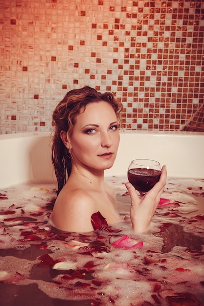 Young woman with red hair take bubble bath with candle.