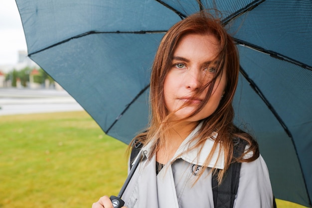 Giovane donna con i capelli rossi con l'ombrello