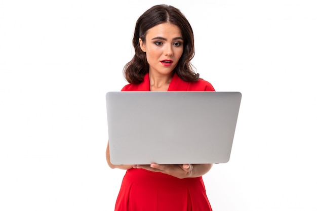 A young woman with red lips, bright makeup, works with a white laptop