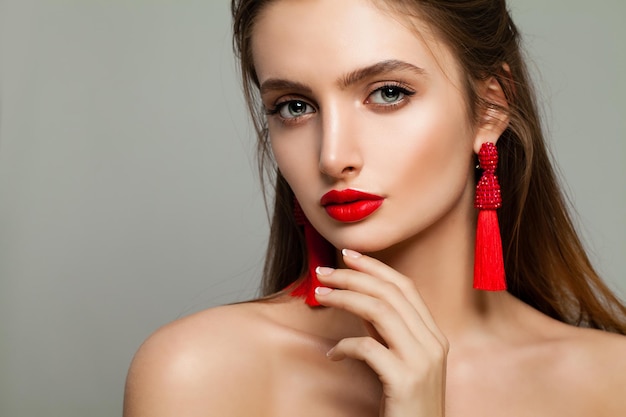 Young Woman with Red Lips Makeup and Jewelry Earrings. Beautiful Model, Cute Face