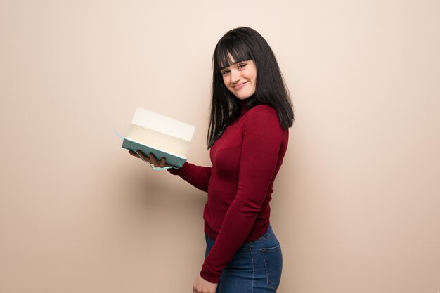 Young woman with red turtleneck holding a book and enjoying reading