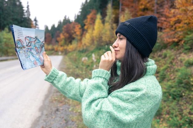 A young woman with a road map in the forest in the mountains