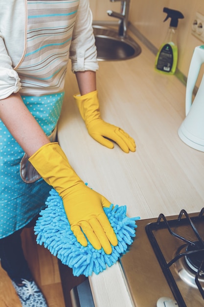 Молодая женщина с резиновыми перчатками, уборка кухни