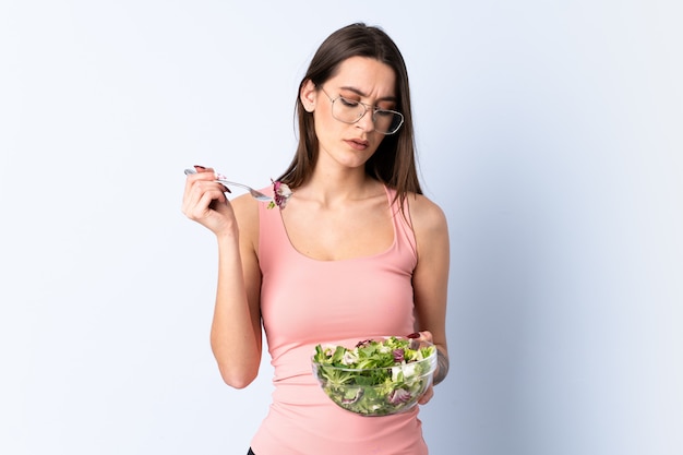 Young woman with salad over isolated wall