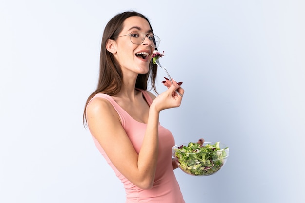 Young woman with salad over isolated wall