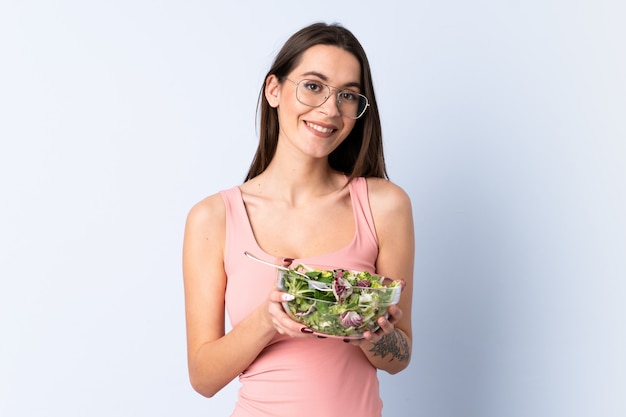 Young woman with salad over wall