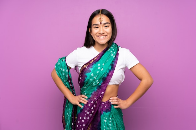 Young woman with sari over posing with arms at hip and smiling