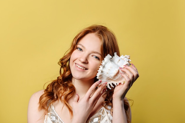 young woman with a sea shell to her ear