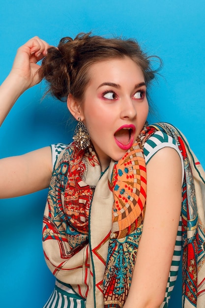 Young woman with shocked facial expression on blue background