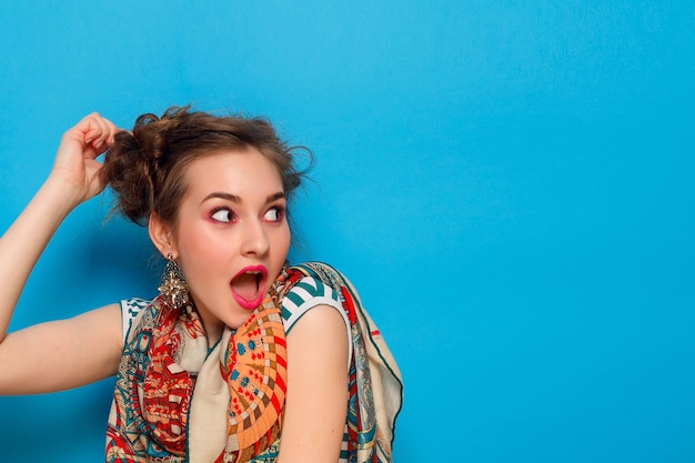 Young woman with shocked facial expression on blue background